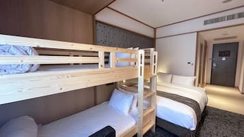 A hotel room with bunk beds, a sofa, and a door.