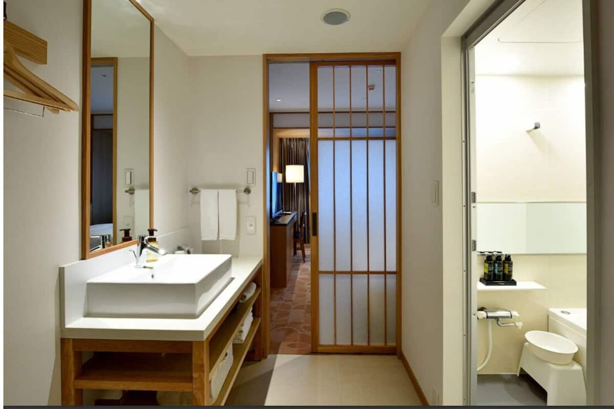 A traditional Japanese-style bathroom with a sink, toilet, and a sliding door leading to a hallway.