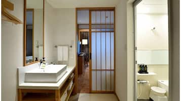 A traditional Japanese-style bathroom with a sink, toilet, and a sliding door leading to a hallway.