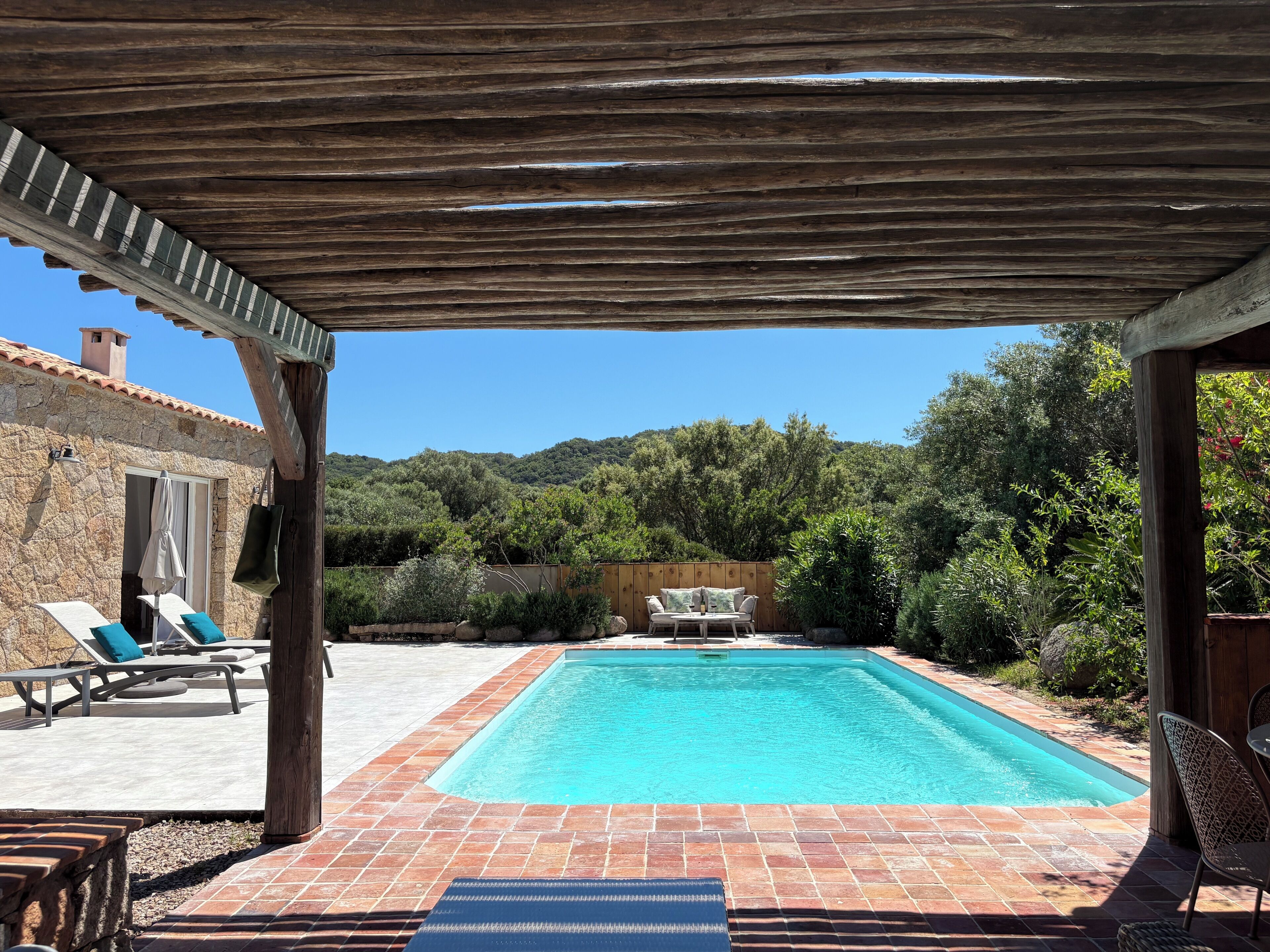 Une piscine extérieure couverte, dotée de chaises longues, avec un bâtiment en pierre en arrière-plan.