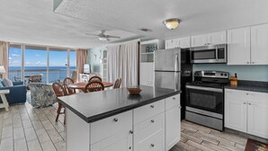 A modern kitchen with white cabinets, stainless steel appliances, and a large island. - Garden City Beach Oceanfront Condo 609 | Rising Tides Properties Rental (Murrells Inlet)
