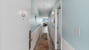 A hallway with light blue walls, white trim, and a patterned rug. - Garden City Beach Oceanfront Condo 609 | Rising Tides Properties Rental (Murrells Inlet)