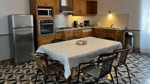 Cozinha compacta com armários de madeira, geladeira de aço inoxidável, forno, micro-ondas e fogão a gás.