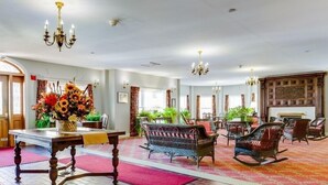 A spacious lobby with a wooden table, wicker chairs, and a floral arrangement. - Originally built in Chautauqua Institution in 1890, the original St. Elmo Hotel building was torn down and rebuilt as a residential condominium.  It now offers the convenience of an elevator; (Chautauqua)