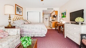 A bedroom with a bed, a desk, a television, and a dining area. - Originally built in Chautauqua Institution in 1890, the original St. Elmo Hotel building was torn down and rebuilt as a residential condominium.  It now offers the convenience of an elevator; (Chautauqua)