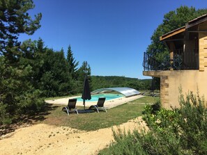 A pool area with two lounge chairs and a covered swimming pool, surrounded by trees and a building with a balcony. - Beautiful house, no neighbors, very quiet, 5 km from Castelnaud, Beynac, and Domme (Saint-Cybranet)
