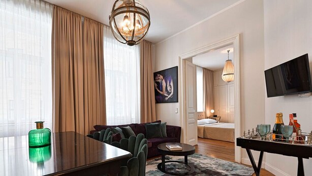 Une chambre d’hôtel moderne avec un coin repas, un canapé, une télévision et un tableau au mur.