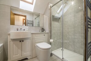 A modern bathroom with a skylight, a glass shower enclosure, and a white sink. - French Fields - 4 Bedroom - St Florence (Tenby)