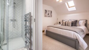 A bedroom with a bed, bedside table, and a window. - French Fields - 4 Bedroom - St Florence (Tenby)