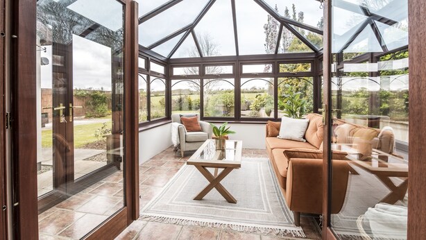 A conservatory with a glass ceiling, furnished with a sofa, armchairs, and a coffee table. - French Fields - 4 Bedroom - St Florence (Tenby)