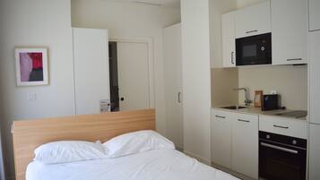 A hotel room with a bed, a kitchenette with a microwave, a coffee maker, and a sink.