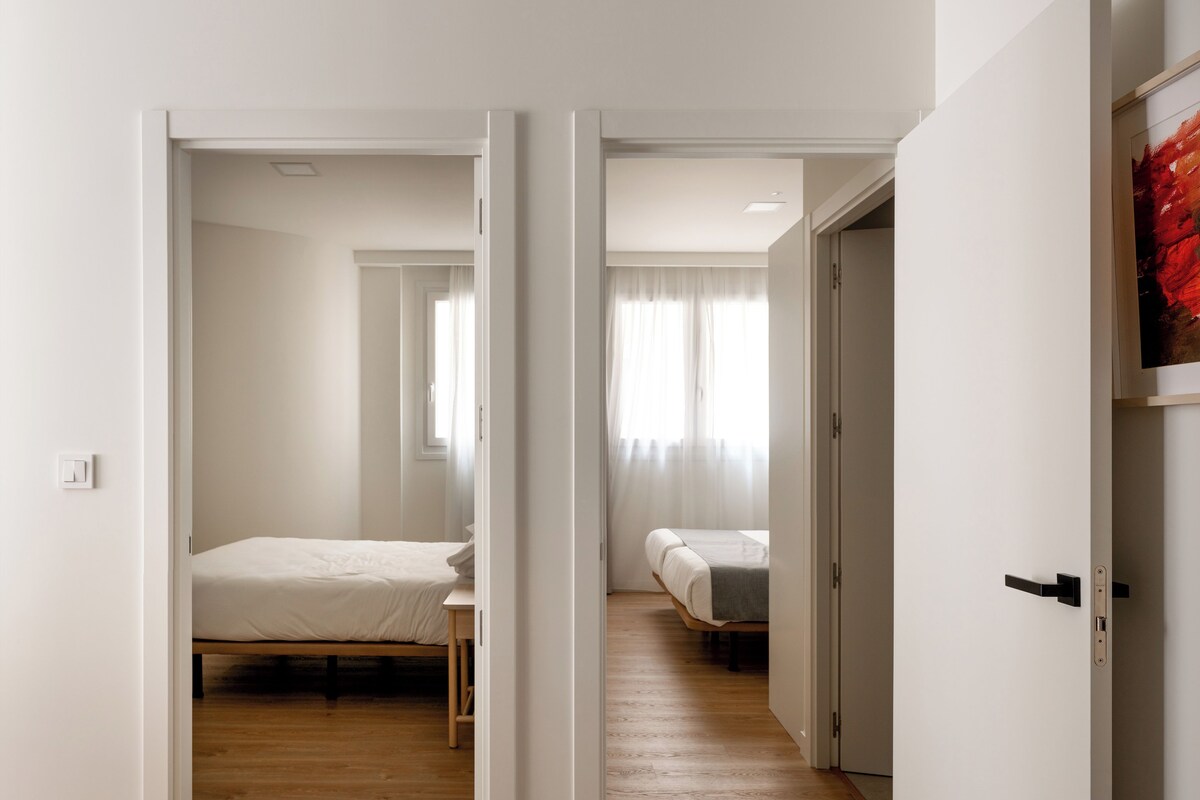 A spacious, well-lit room with a wooden floor, a bed, and a desk.