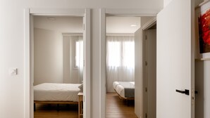 Een ruime, goed verlichte kamer met een houten vloer, een bed en een bureau.