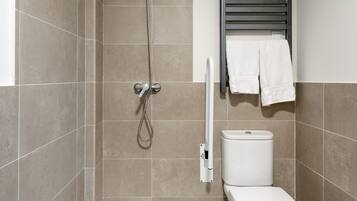 Een moderne badkamer met douche, toilet en handdoekhouder.