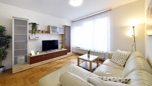 Ein modernes Wohnzimmer mit einer Couch, einem Fernseher und einer Pflanze.