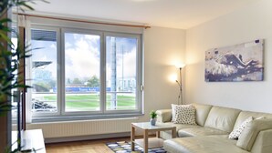 Ein Wohnzimmer mit großem Fenster, einer Couch, einem Couchtisch und einem Bild an der Wand.
