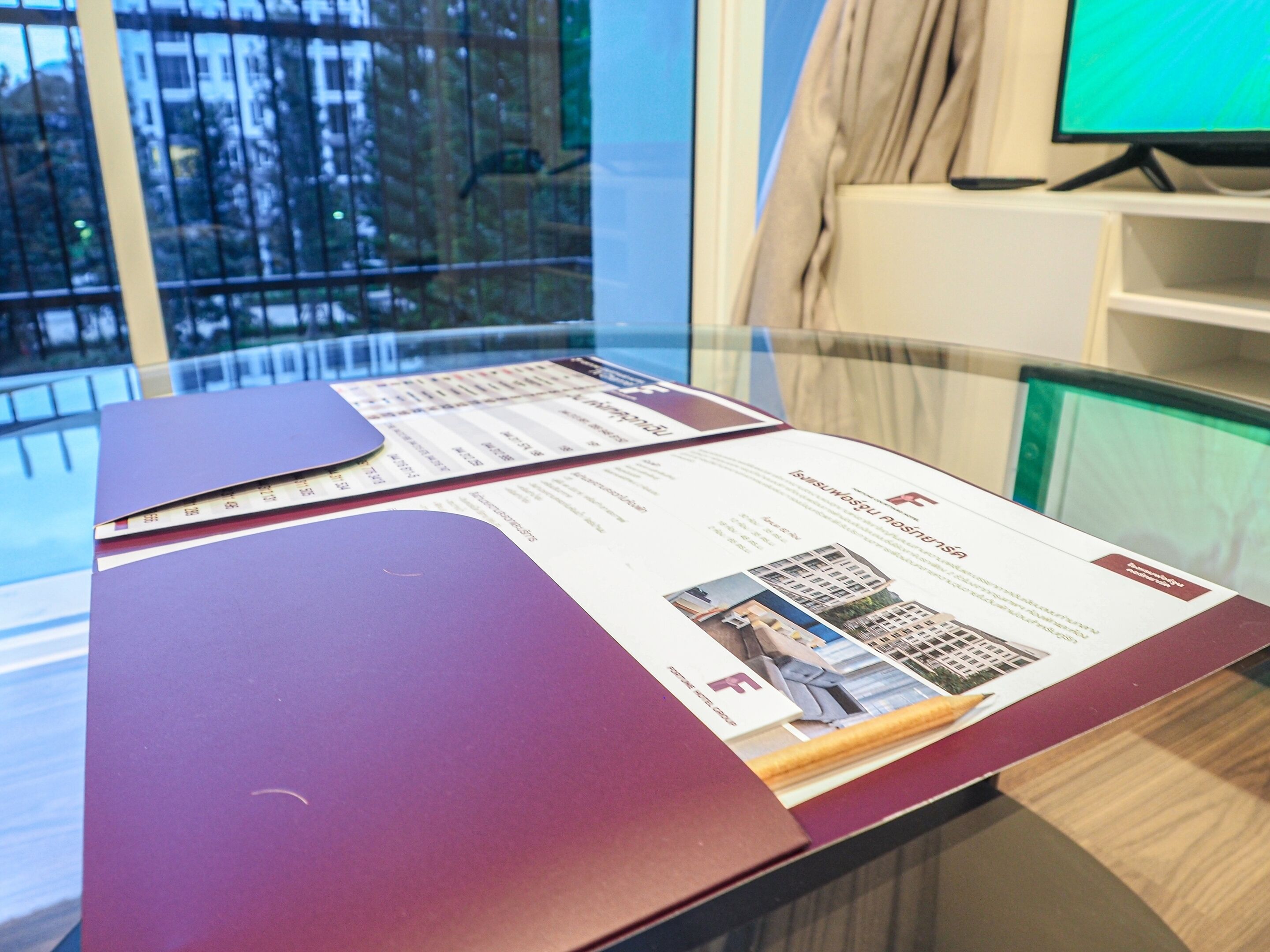 Een glazen tafel met brochures en een map.