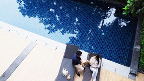 A poolside area with two lounge chairs and a table with a drink and snacks. - Fortune Courtyard Khao Yai Hotel Official (Pak Chong)