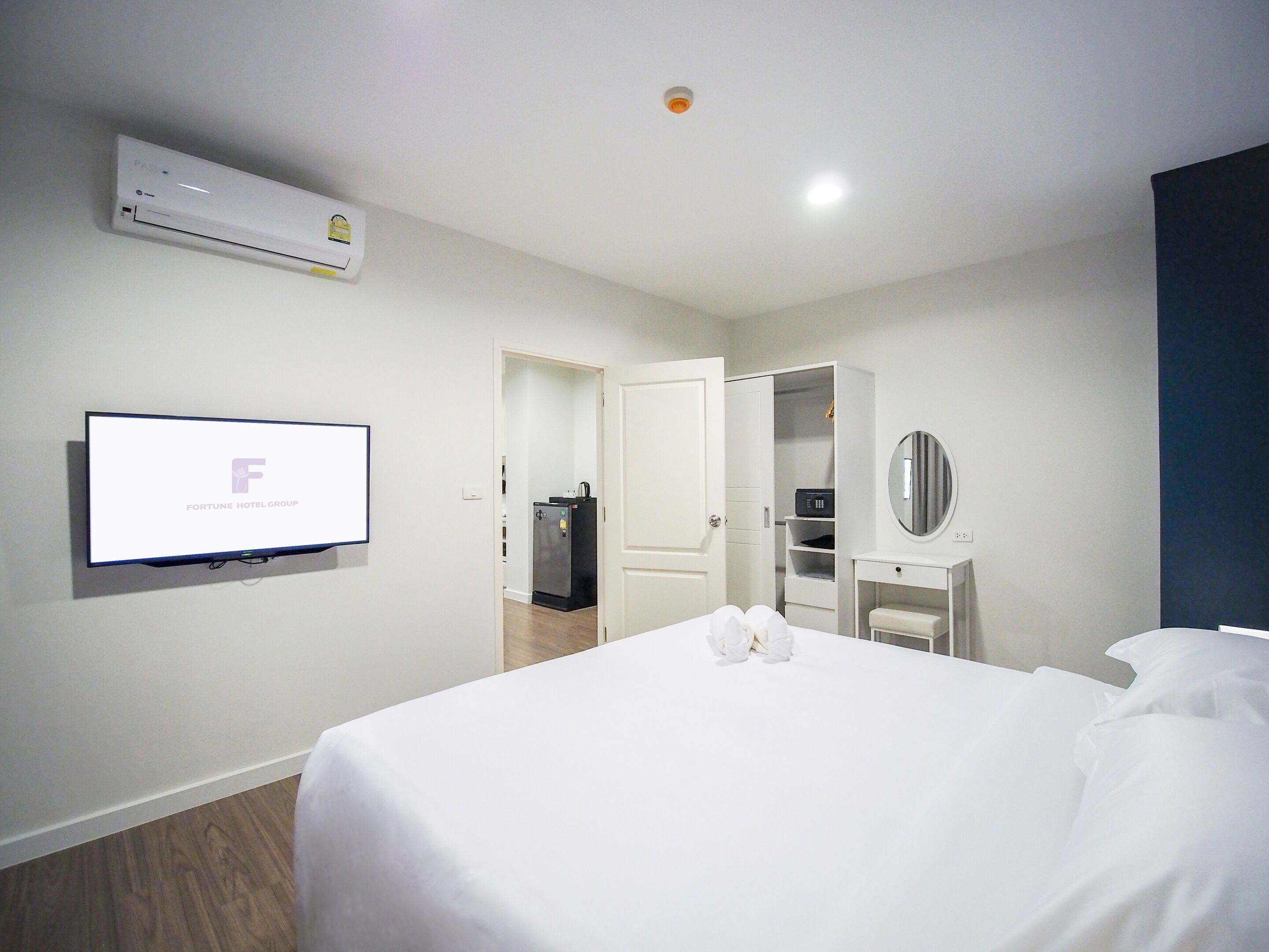 Une chambre d’hôtel avec un lit, un téléviseur fixé au mur, une armoire et un miroir.