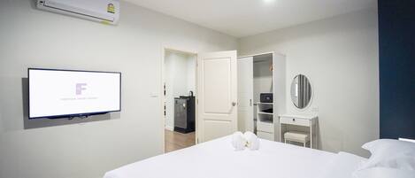Une chambre d’hôtel avec un lit, un téléviseur fixé au mur, une armoire et un miroir.