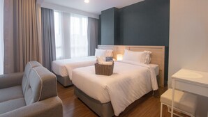 A hotel room with two beds, a sofa, a bedside table, and a window with curtains. - Fortune Courtyard Khao Yai Hotel Official (Pak Chong)