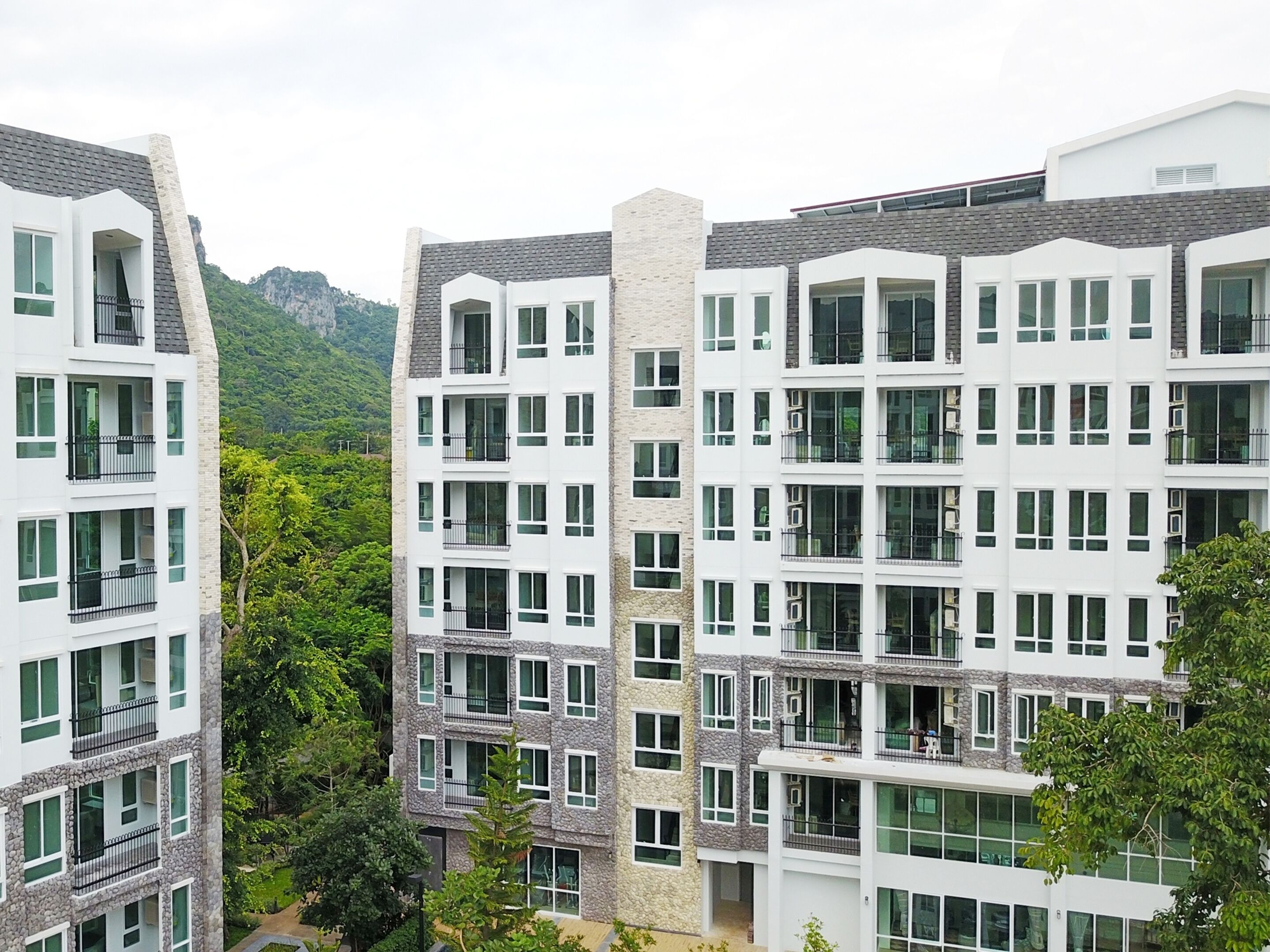 A multi-story residential building with balconies, large windows, and a stone facade.