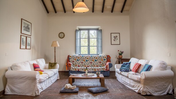 A cozy living room with two white sofas, a wooden coffee table, and a floral sofa. A window with a view of greenery is in the center. - BigTypicalTuscan farmhouse, breath-taking views, big private outdoor, pool to share (Sarteano)