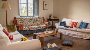 A living room with a floral sofa, a white sofa, a wooden coffee table, and a bench with cushions. - BigTypicalTuscan farmhouse, breath-taking views, big private outdoor, pool to share (Sarteano)