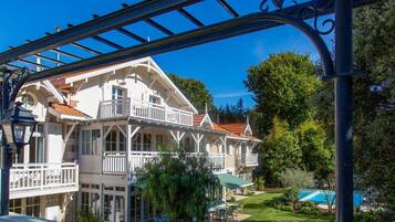 Ein großes, weißes, zweistöckiges Gebäude mit einem Balkon und einem Pool im Hintergrund.