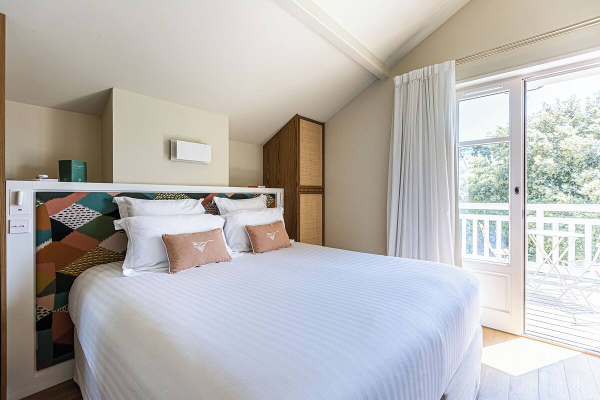 Un dormitorio con una cama grande, un armario de madera, una ventana con cortinas y vistas al exterior.