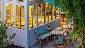 An outdoor patio with wicker furniture and a glass enclosure.