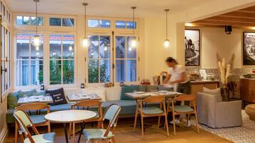 Un coin repas chaleureux, avec des meubles en bois, de grandes fenêtres et des luminaires suspendus.