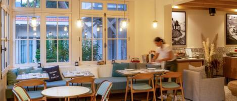 A cozy dining area with wooden furniture, large windows, and pendant lighting.