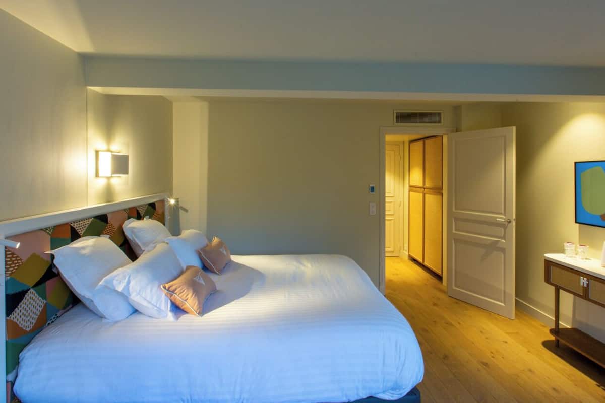 Una habitación de hotel con cama, mesita de noche y televisor montado en la pared.