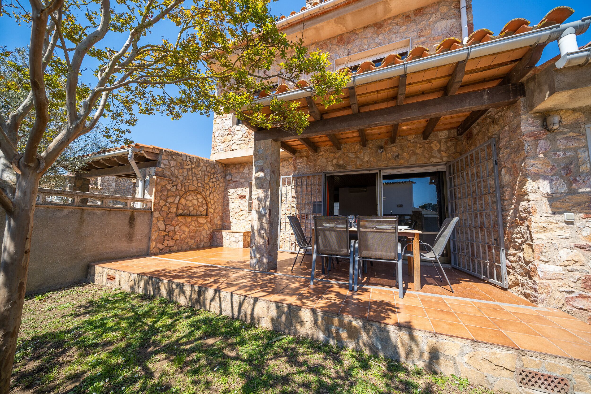 A patio with stone walls, a wooden pergola, and outdoor furniture.