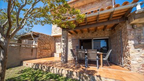 Une terrasse avec des murs en pierre, une pergola en bois et du mobilier d’extérieur.
