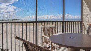 Ein Balkon mit Blick auf den Strand, einem Tisch und zwei Stühlen.