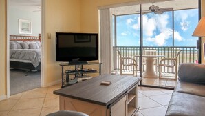 Ein Hotelzimmer mit Balkon, Fernseher, Sofa und Esstisch.