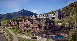 Un resort con varias cabañas de madera y un edificio grande con balcones, todo ello con montañas al fondo.