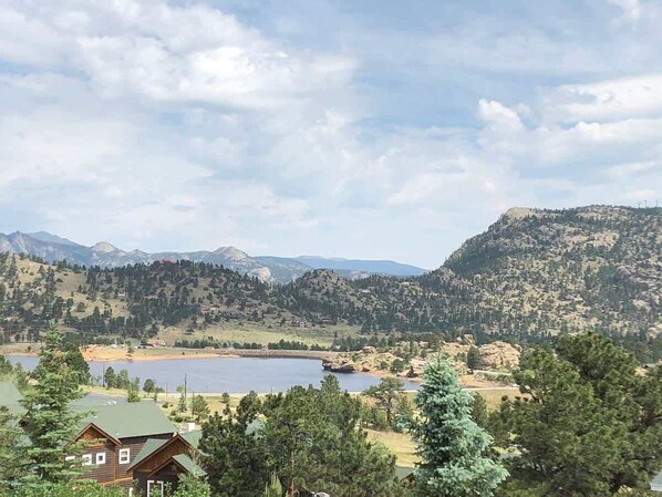 Un paisaje montañoso con un lago, casas y árboles.