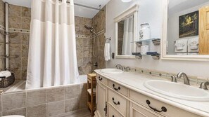 A bathroom with a shower, a double sink vanity, and a large mirror.