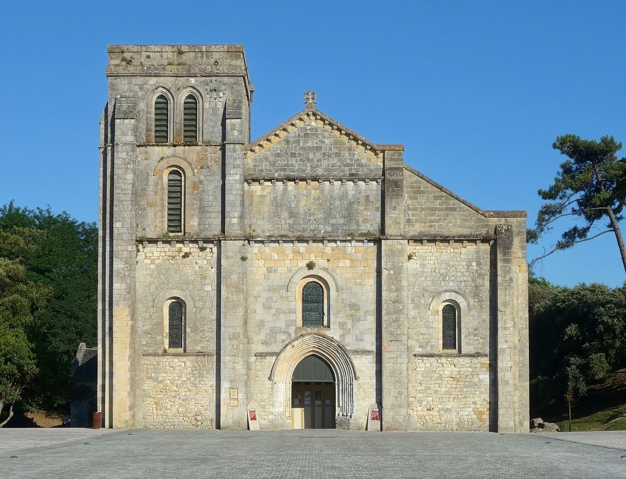 Una iglesia histórica de piedra con una entrada central en arco, dos torres de campanas y un frontón triangular.