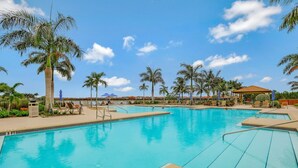 A swimming pool with multiple lanes, surrounded by palm trees and lounge chairs. - Beachy Condo in Artesia | Pool, Gym & Pickleball (Naples)
