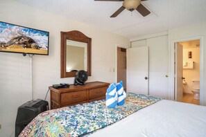 A bedroom with a bed, a dresser, a mirror, a ceiling fan, and a television on the wall. - Kamaole Sands #5-313 Idyllic Ocean Courtyard View, Across from Beach! A/C (Kihei)