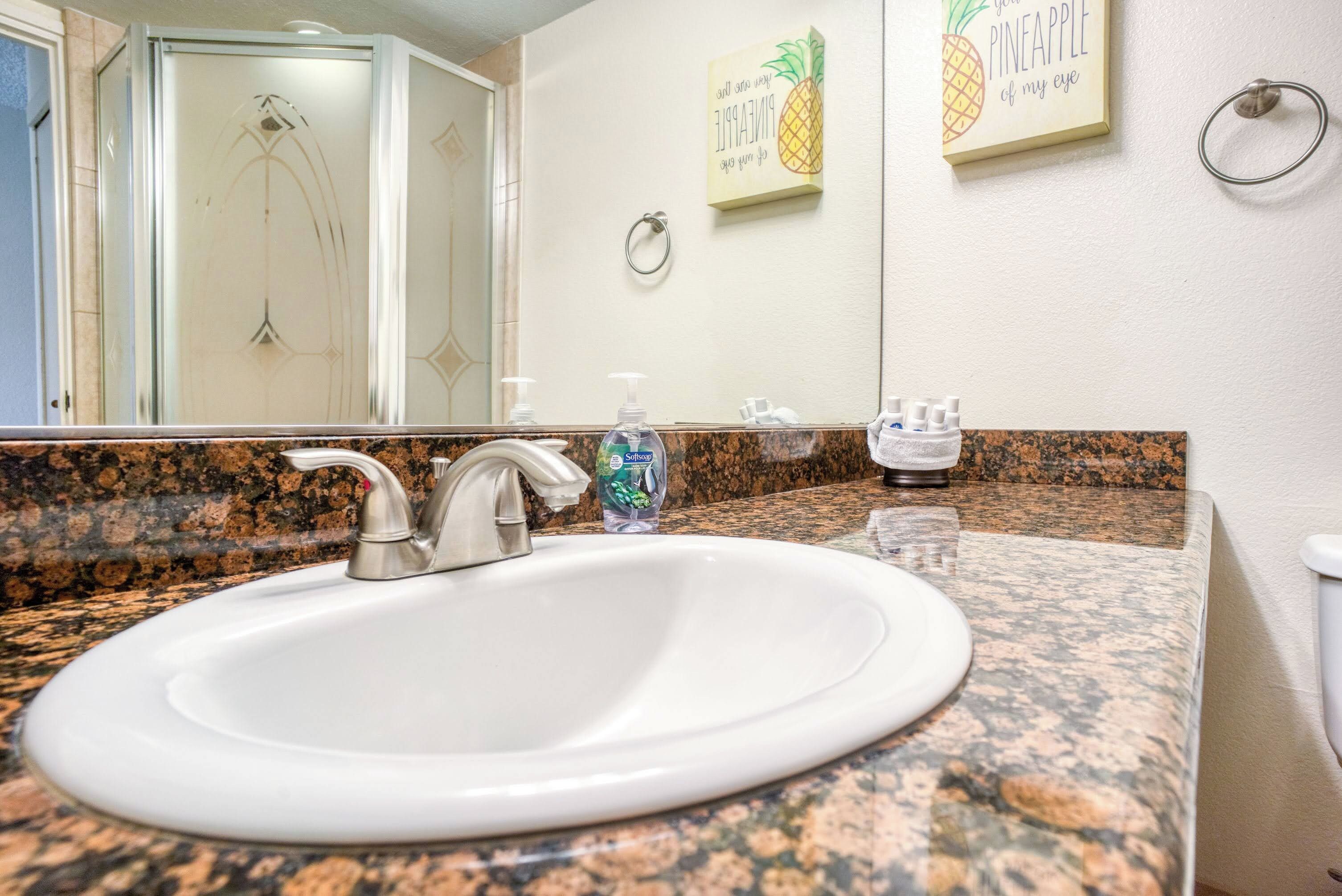 A bathroom with a white sink, granite countertop, and two hand soap dispensers.