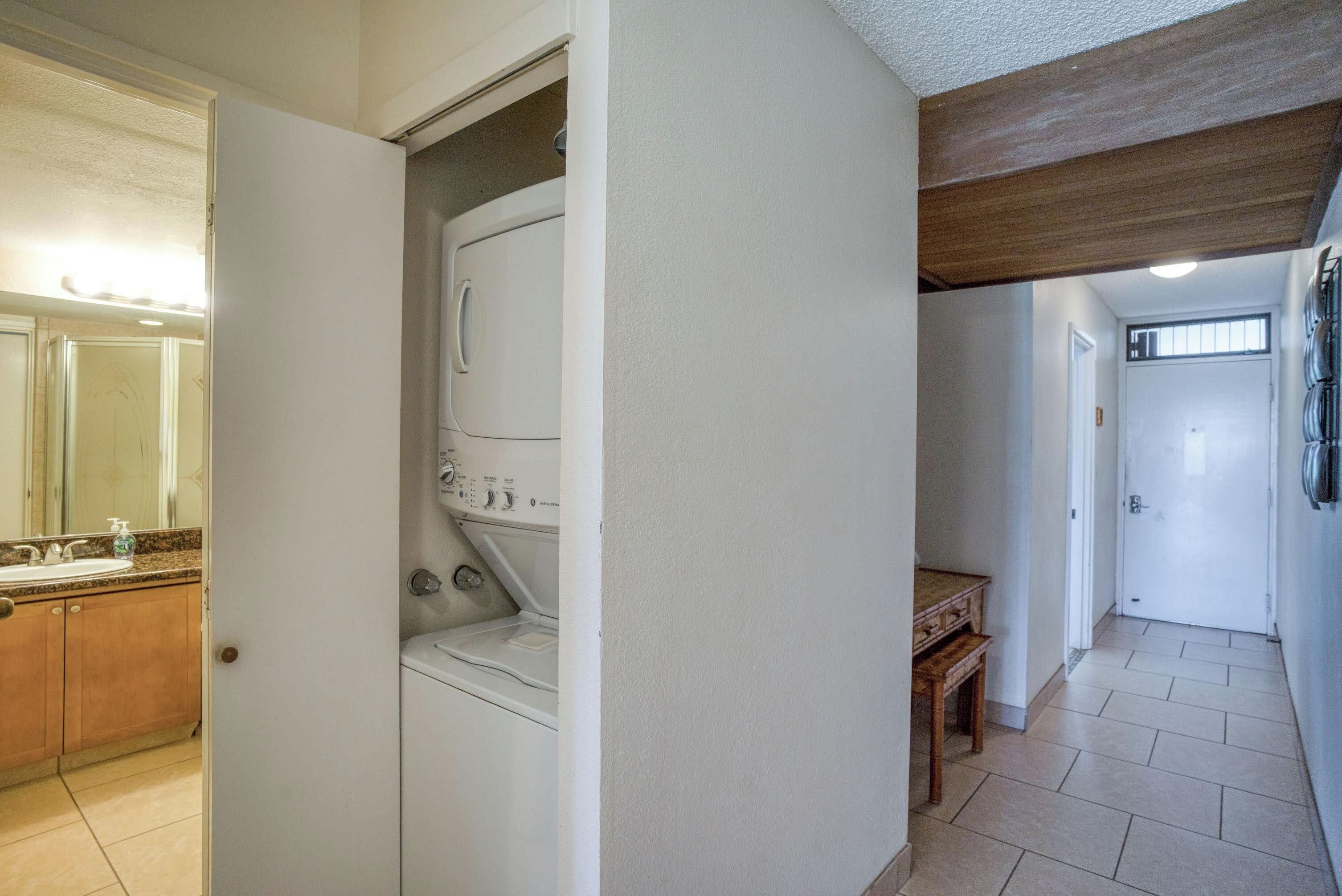 A laundry room with a washing machine, a wooden table, and a mirror.