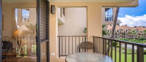 A balcony with a glass door, a round table, and a wicker chair.