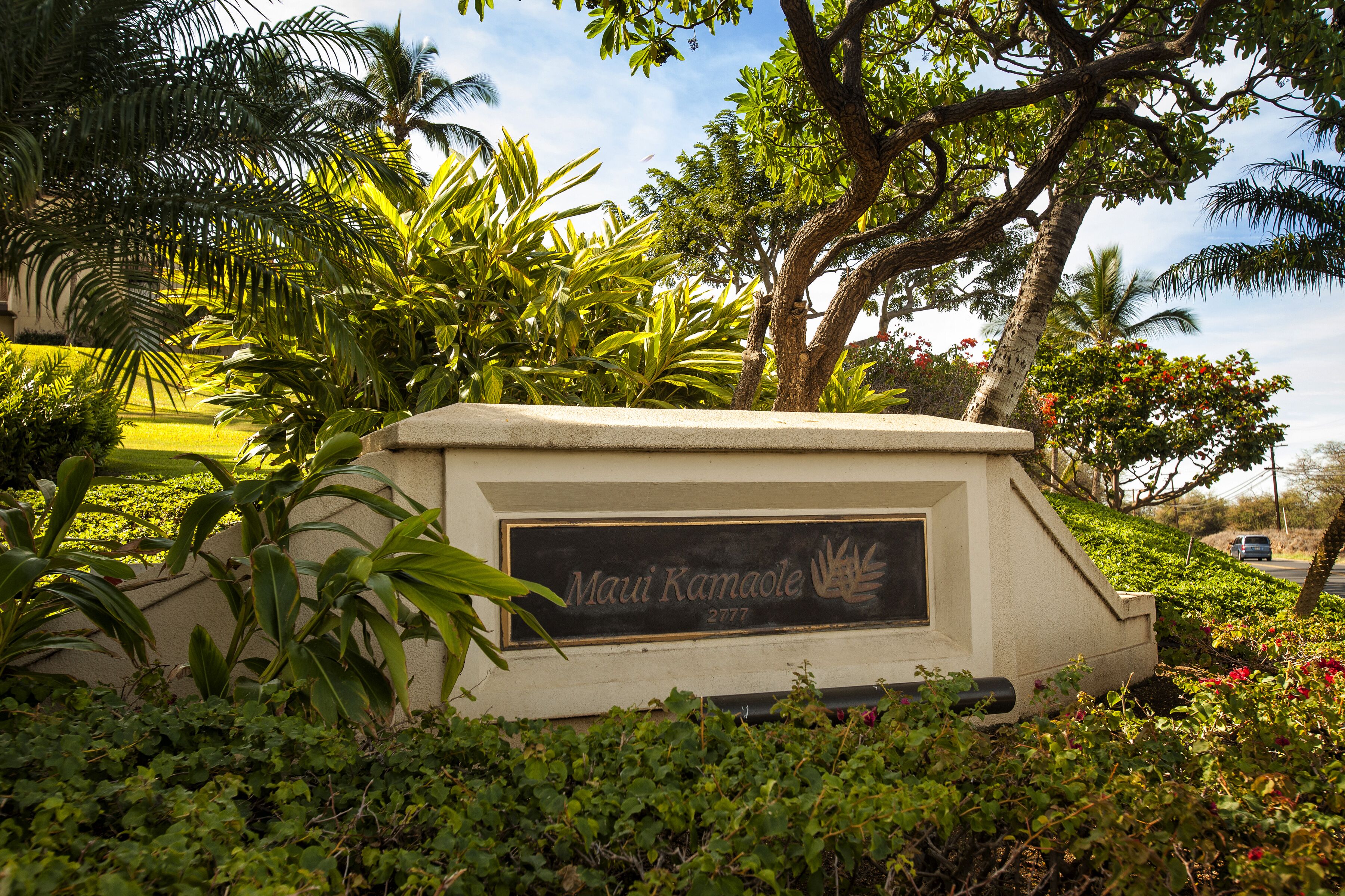 A sign with the name 'Maui Kamaole' and the number 2777, surrounded by lush greenery and palm trees.