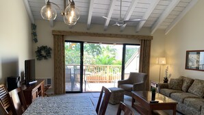 Amplia sala de estar con una mesa de comedor, sillas, un sofá y un balcón con vistas a zonas verdes.
