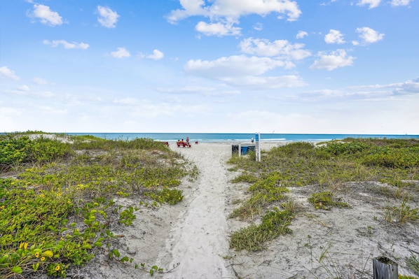 A sandy beach path leading to a structure with a view of the ocean.